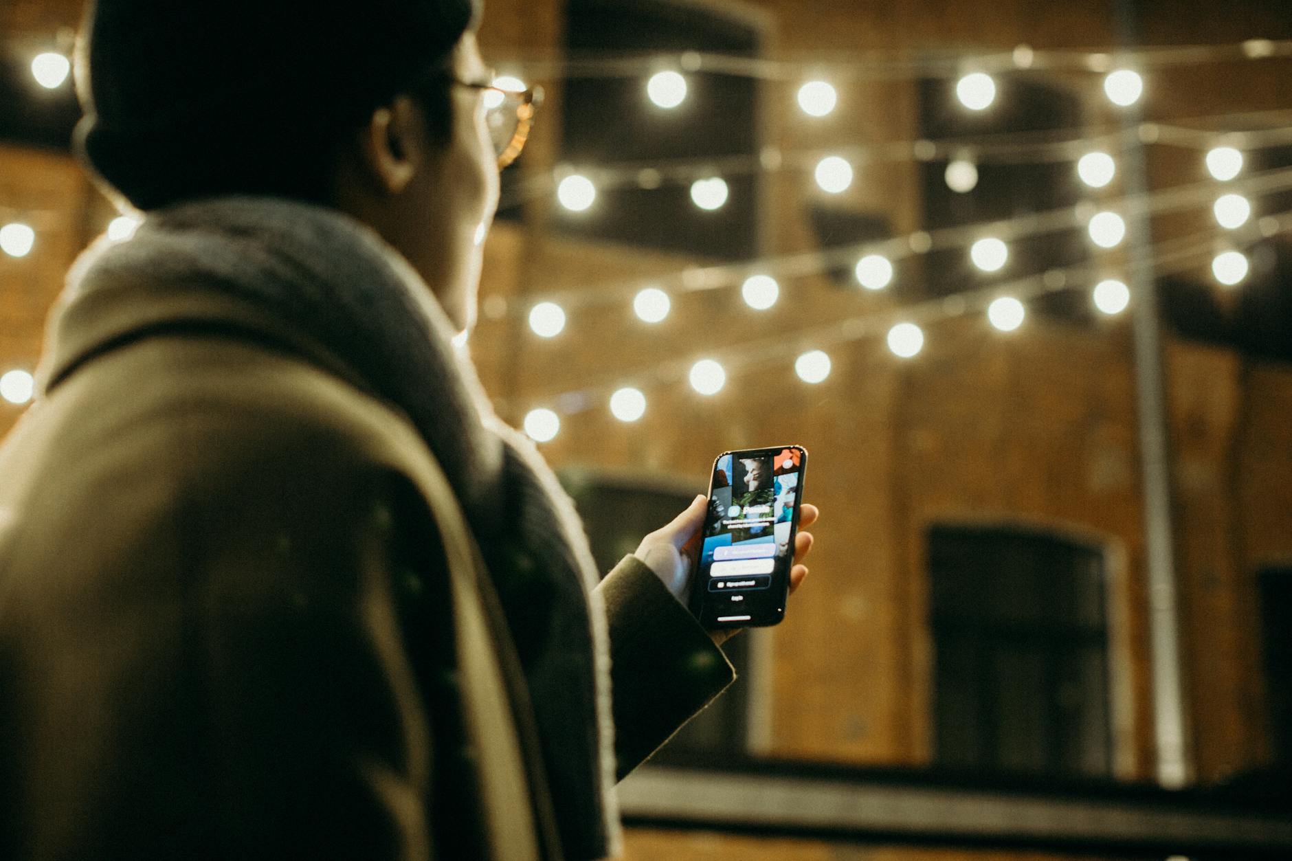 Person looking at a phone in soft warm bar lighting